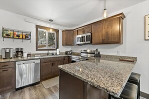 A modern kitchen with granite countertops, stainless steel appliances, and wooden cabinets. - Hillside Haven, Hot Tub, Private (Lead)