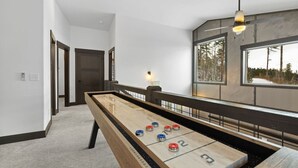 Une table de jeu de «shuffleboard» avec des cases numérotées, un ventilateur de plafond et une fenêtre donnant sur des arbres.