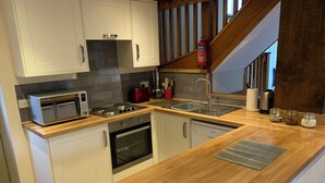 A modern kitchen with white cabinets, a wooden countertop, a built-in oven, a toaster, and a stainless steel sink.