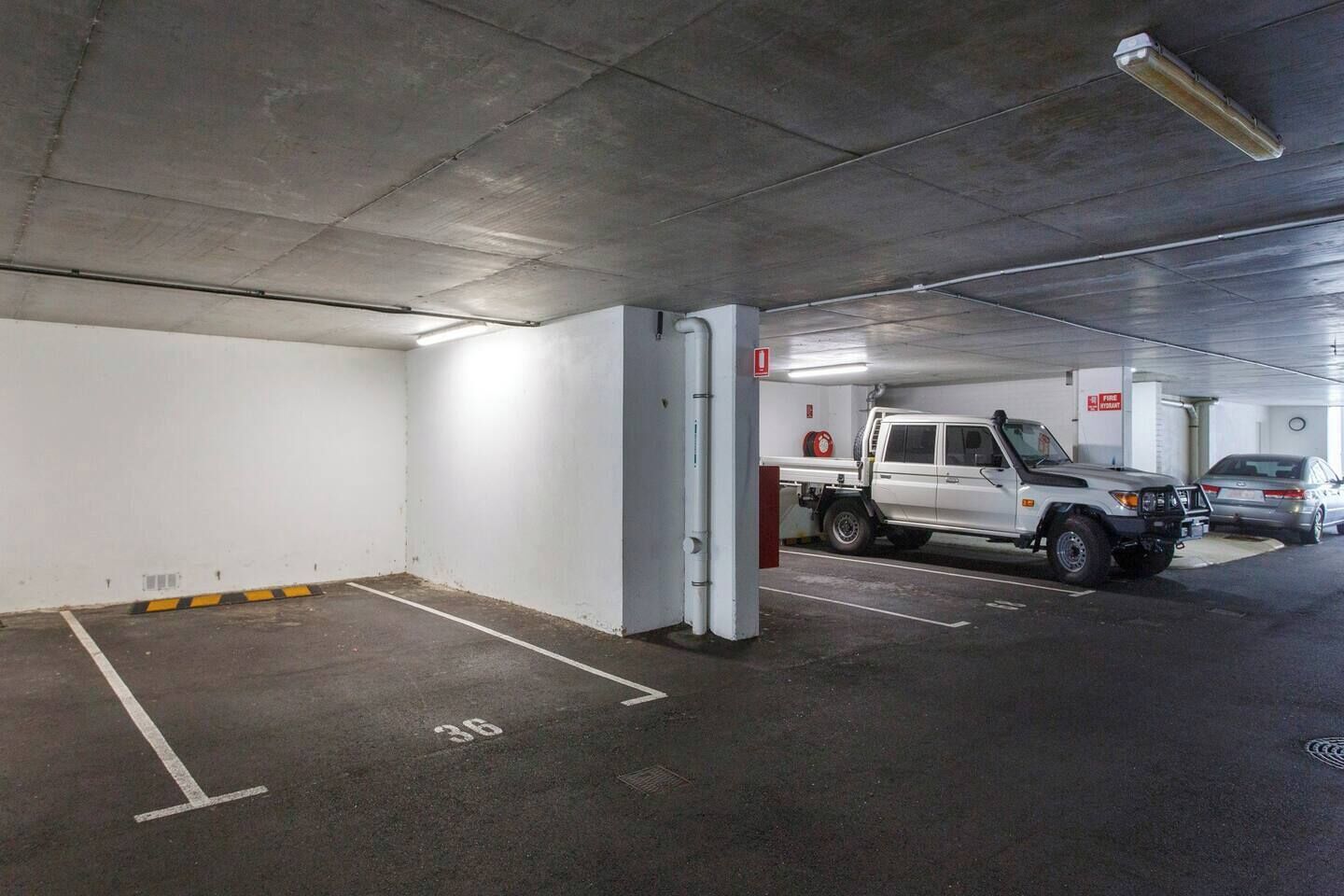 An underground parking garage with a white pickup truck parked in a designated space.