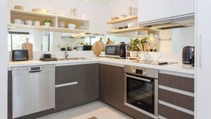 Una cuina moderna amb electrodomèstics Bosch integrats, armaris de fusta i una illa gran amb rentatge.