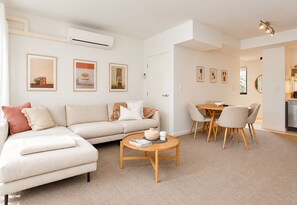 A modern living room with a sofa, coffee table, and dining area.