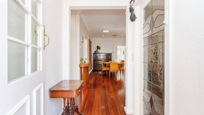 A hallway with a wooden table, a dining area with chairs, and a kitchen in the background. - This house is a 2 bedroom(s), 2 bathrooms, located in Fremantle, WA. (Fremantle)