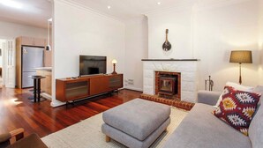 A modern living room with a fireplace, a television, and a sofa. - This house is a 2 bedroom(s), 2 bathrooms, located in Fremantle, WA. (Fremantle)