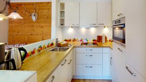 A modern kitchen with white cabinets, a wooden countertop, and a built-in oven. - Welcome to the cozy holiday apartment Alberta! (Garmisch-Partenkirchen)