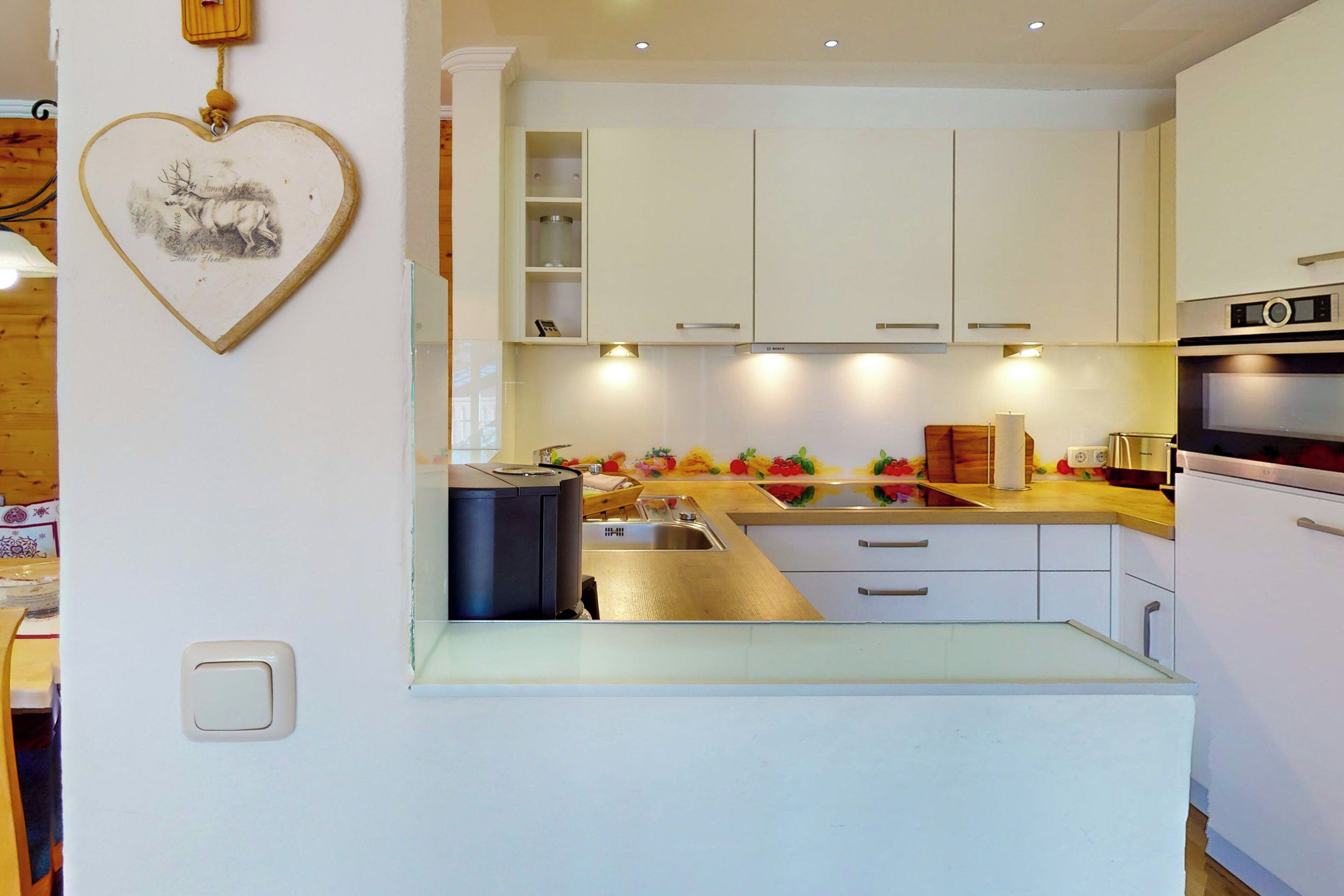Een moderne keuken met witte kastjes, een roestvrijstalen spoelbak en een inbouwoven.