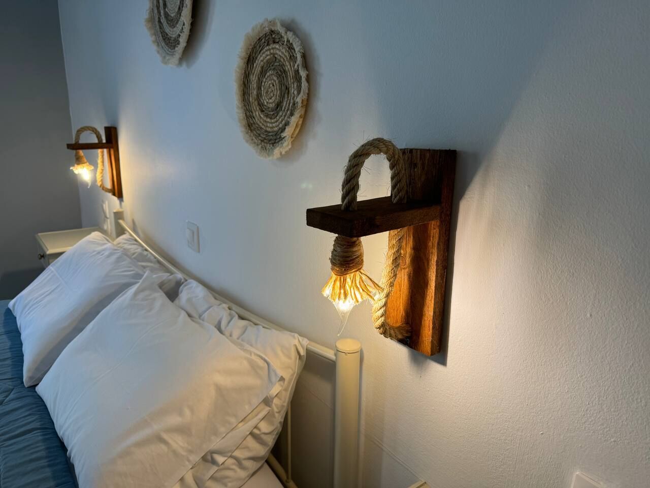 A bedroom with a bed, a wall-mounted light fixture, and a textured wall decoration.