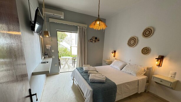 A bedroom with a bed, bedside tables, a TV, and a window with curtains.