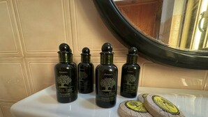 A bathroom sink with four bottles of Amari Olive Tree Shampoo and Shower Gel, and two bars of soap.