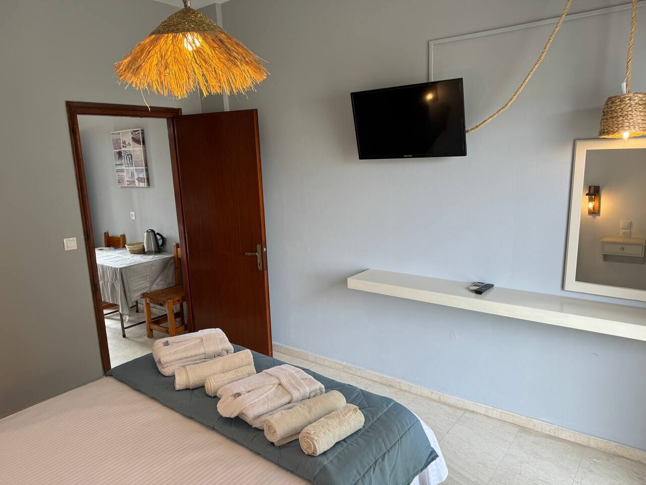 Een slaapkamer met een bed, een televisie, een hanglamp en een deur naar een badkamer.