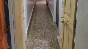 Un pasillo estrecho con puertas de madera a ambos lados, que da a una habitación con suelo de baldosas.