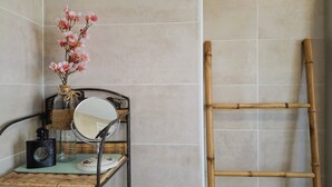A bathroom with a vanity, a mirror, a vase with flowers, a bamboo ladder, and a bottle of shampoo. - Warm and Authentic! The watchmaker’s house, downtown Crozon (Crozon)