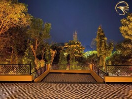 Vista nocturna de un jardín con suelo estampado y barandilla de metal.
