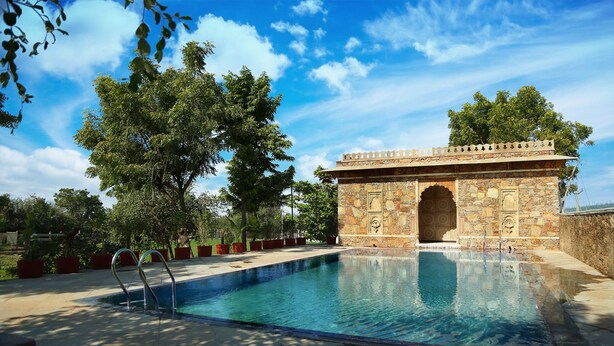 Ein Schwimmbecken mit Steinarchitektur und wolkenlosem, blauem Himmel.