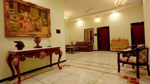 Eine geräumige Lobby mit Marmorboden, einem großen, aufwendigen Gemälde, einem klassischen Holzkonsole und einer Chandelüster.