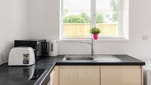 A modern kitchen with a black countertop, a white toaster, a kettle, and a sink. - Kingston Richmond Lux Brand new Studio (Kingston Upon Thames)