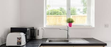 A modern kitchen with a black countertop, a white toaster, a kettle, and a sink.