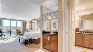 Une chambre d’hôtel dotée d’un grand lit, d’un coin salon avec vue, d’un coin cuisine et d’une salle de bain avec un grand miroir.