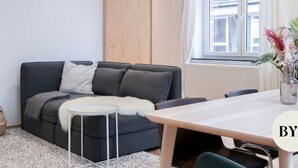 A modern living room with a dark grey sofa, a small round table, and a wooden dining table. - Beautiful apartment in Liège center - 1st floor (Liège)
