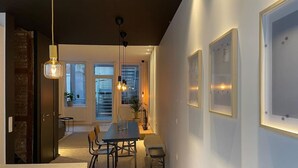 Uma sala de jantar moderna com uma mesa e cadeiras, um banco, iluminação pendente e quadros nas paredes.
