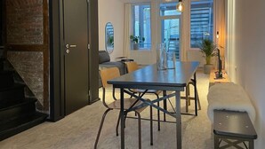 Uma área de refeições moderna com uma mesa comprida, cadeiras e luminárias pendentes.