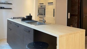 Uma cozinha moderna com uma ilha central, forno embutido e luminária pendente.