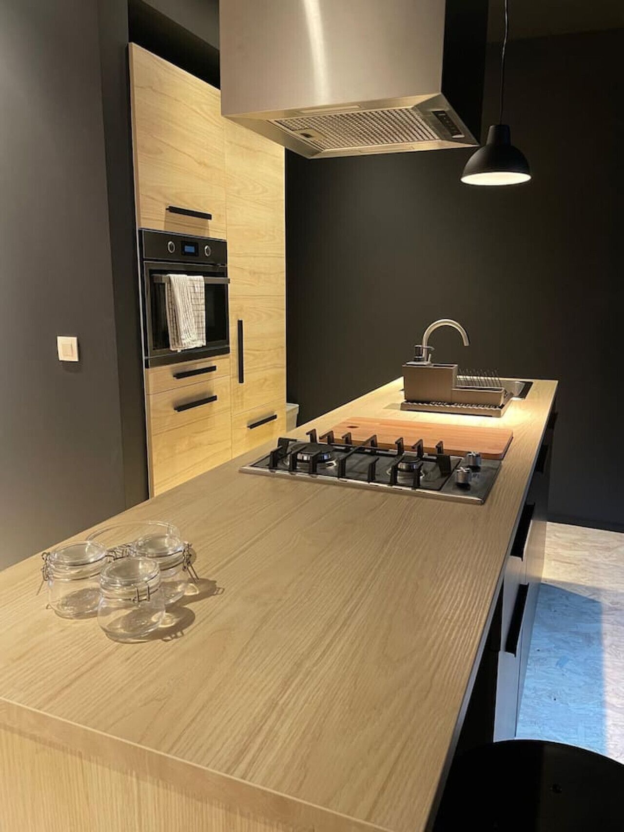Een moderne keuken met een houten aanrecht, een ingebouwde oven, een gasfornuis en een spoelbak.