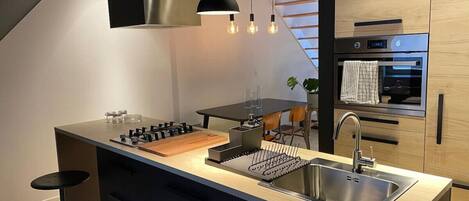 A modern kitchen with a central island, stainless steel appliances, and pendant lighting.