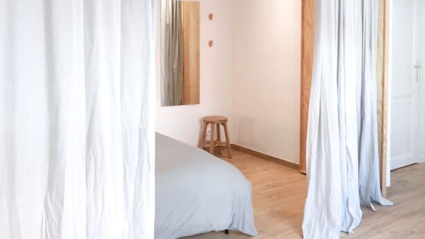 A modern bedroom with a bed, a stool, and a wooden door. - Beautiful apartment in Liège center - 2nd floor (Liège)