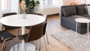A modern living room with a round dining table, dark sofas, and a small white side table. - Beautiful apartment in Liège center - 2nd floor (Liège)