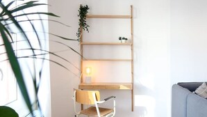 A modern room with a wooden desk, a white chair, a blue sofa, and a potted plant. - Beautiful apartment in Liège center - 2nd floor (Liège)