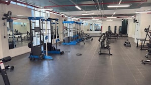 Une salle de sport équipée de divers appareils d’exercice, de miroirs et dotée d’un sol carrelé.