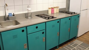 Une cuisine avec des armoires de couleur turquoise, un évier en acier inoxydable et une cuisinière. On peut voir des pots d’épices sur le plan de travail.