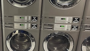 Une rangée de quatre machines à laver identiques, de qualité professionnelle, dotées de panneaux de commande et d’écrans numériques.