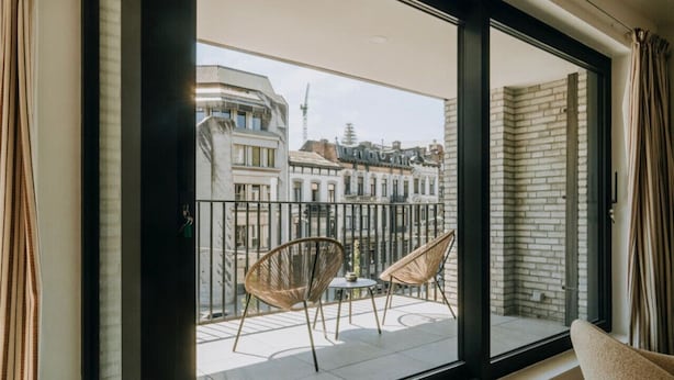 A balcony with two wicker chairs and a small table, overlooking a cityscape with historic buildings. - Apt. 2 chambres + garage en plein centre de Liege (Liège)
