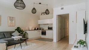 A modern living room with a sofa, coffee table, and a dining area with a kitchen in the background. - Apt. 2 chambres + garage en plein centre de Liege (Liège)