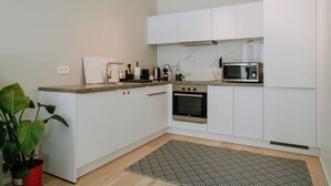 A modern kitchen with white cabinets, a built-in oven, a microwave, and a countertop with a potted plant. - Apt. 2 chambres + garage en plein centre de Liege (Liège)