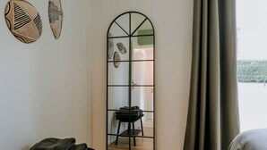 Ein Zimmer mit einem großen Spiegel, einem Bett und Blick ins Freie.