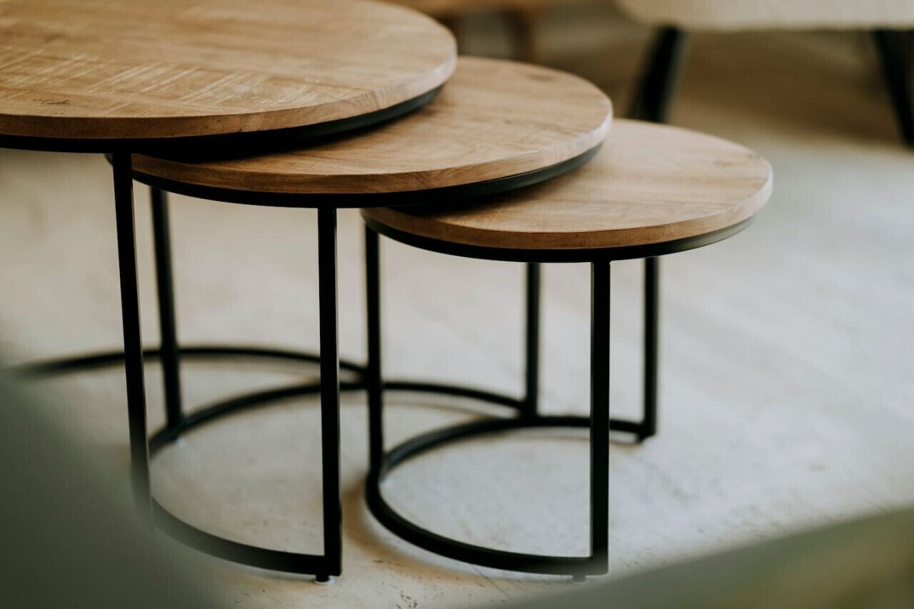 Three round wooden tables with black metal legs.