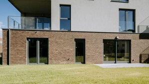 Ein modernes Gebäude mit flachem Dach, großen Fenstern und einer Rasenfläche davor.