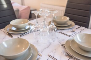 A dining table set with multiple bowls, plates, and wine glasses. - Apt - Sleeps 6 - Pets Ok - Parking (Derby)