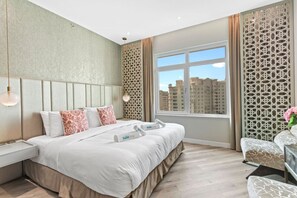 A hotel room with a large bed, a nightstand, a window with a view of buildings, and decorative screens.