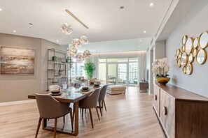Een moderne eethoek met een houten tafel en stoelen, een kroonluchter en een groot raam.