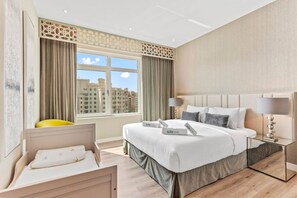 Een hotelkamer met een groot bed, een nachtkastje, een stoel en een raam met uitzicht op gebouwen.