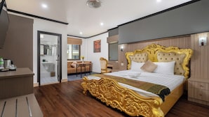 A spacious bedroom with a large bed, a desk, and a bathroom visible through an open door. - Lucky City Hotel (Vientiane)