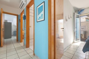Um corredor com paredes azuis, portas de madeira e chão de azulejos.