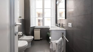 A modern bathroom with a toilet, bidet, and sink, featuring a large window and a towel rack. - Domus Maggiore Apartment (Roma)