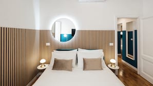 A hotel room with a bed, two bedside tables with lamps, a round mirror, and a wall-mounted air conditioner. - Domus Maggiore Apartment (Roma)