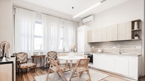 A modern kitchen with white cabinets, a round dining table, and wooden chairs.