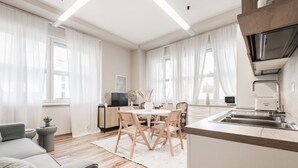 A modern kitchen with a dining area, wooden flooring, and white cabinetry.